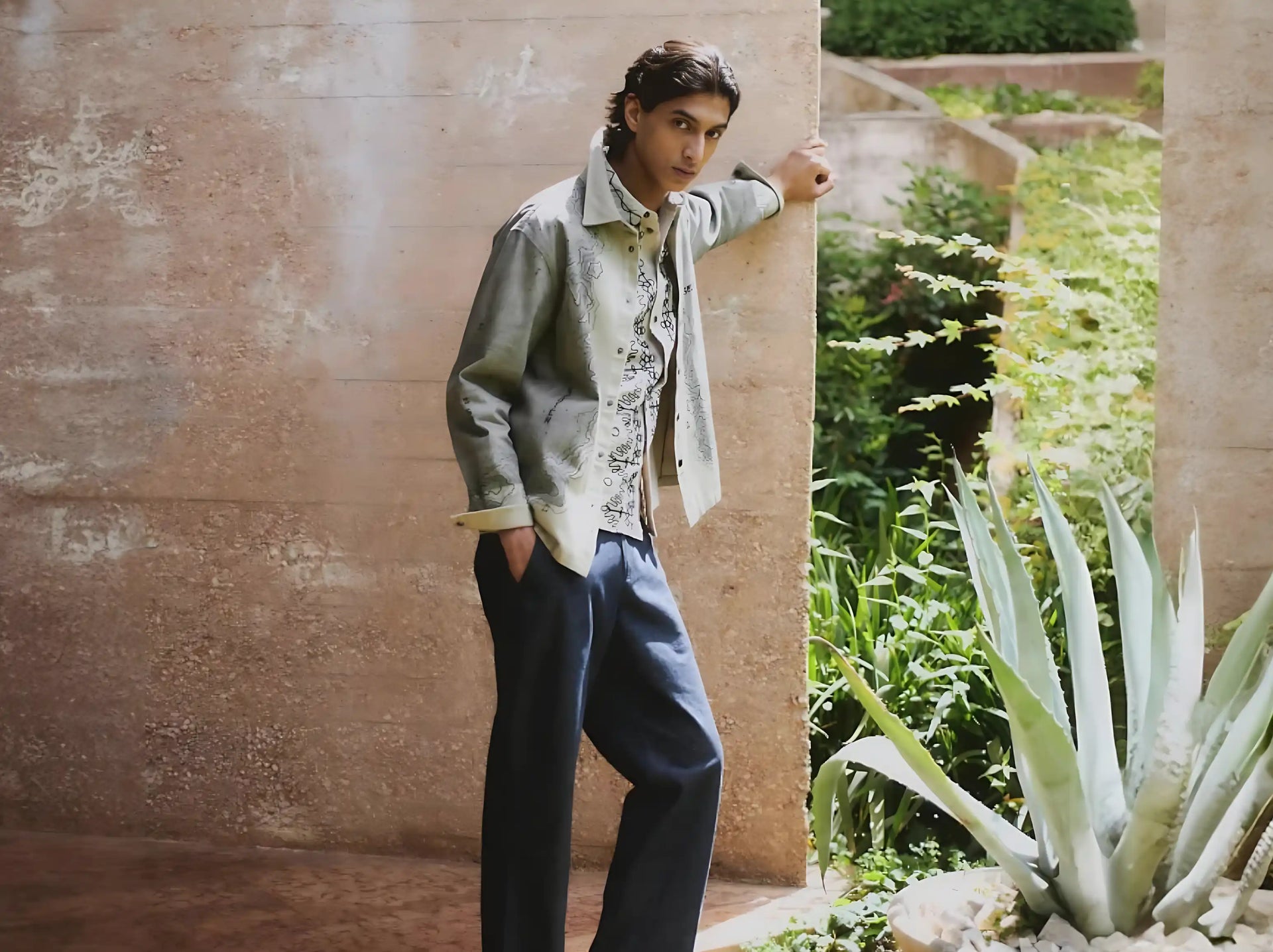 Person standing against a textured wall with a garden scene in the background